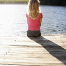 The bliss of “nothing” is what you crave… Young girl sitting by lake